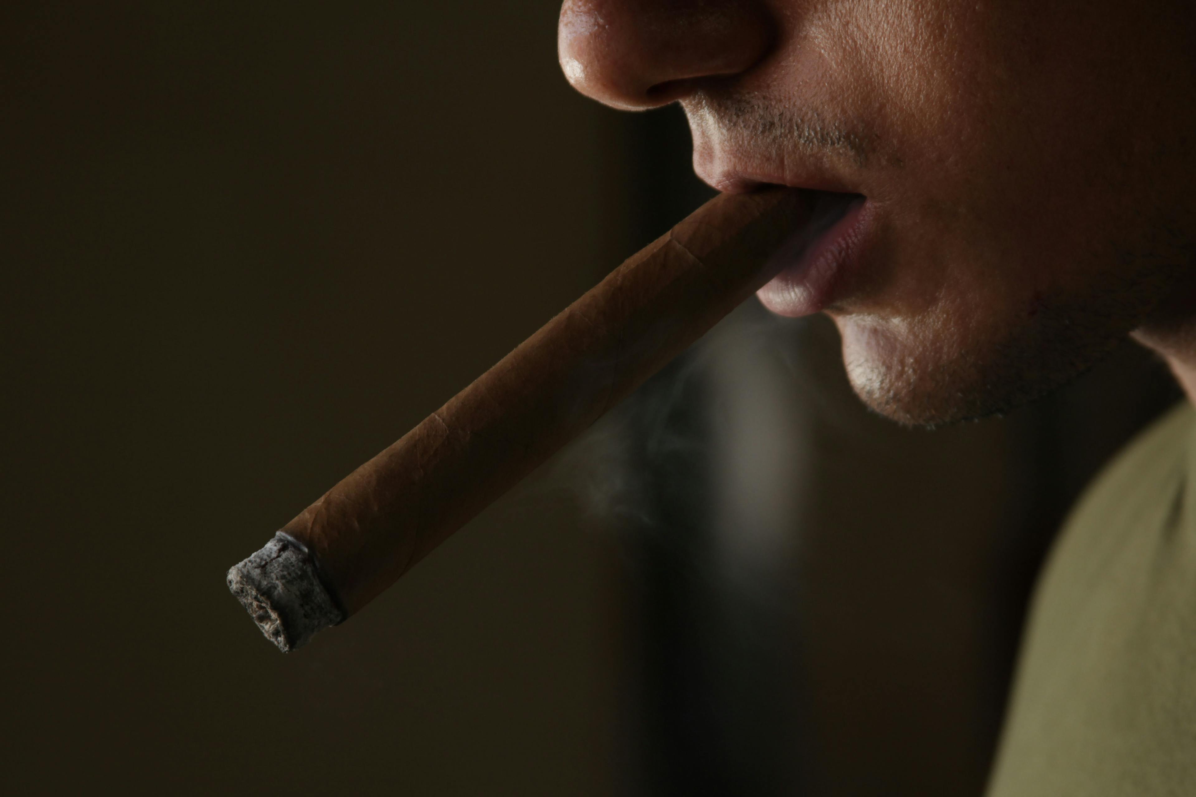 profile shot of man smoking a cigar.